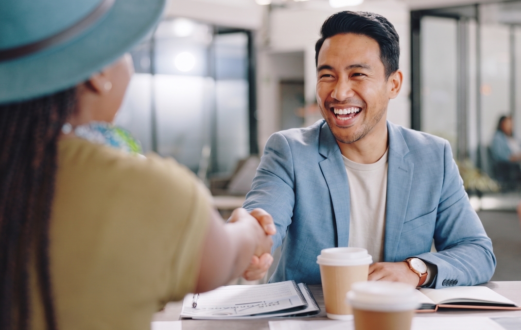 Two colleagues shaking hands across a table