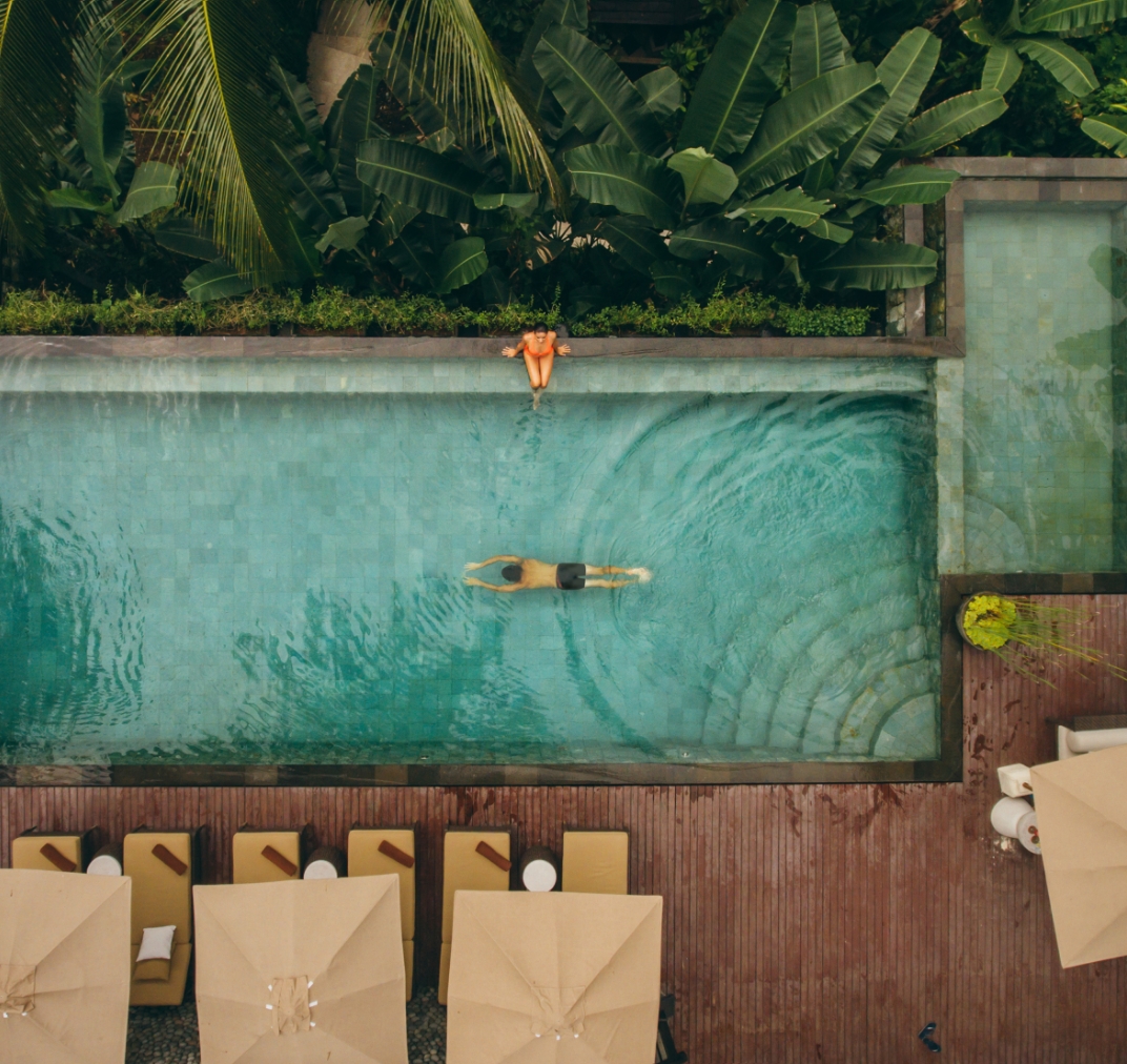 Aerial view of a person floating in a luxury resort pool